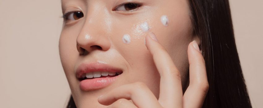 Close,Up,Of,A,Young,Woman,Applying,Moisturizer,To,Her